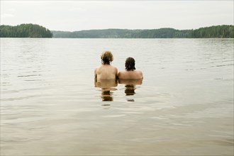 Two young women sitting in the water looking into the distance