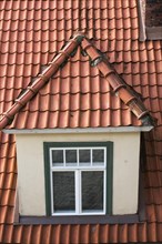 Top view of dormer window on old terracotta roof of residential apartment building