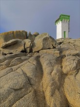 Green and white lighthouse on granite rocks