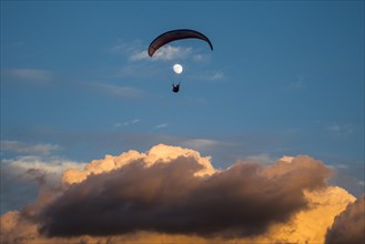 Paragliding in front of the moon above the clouds on the Canary Island of Tenerife