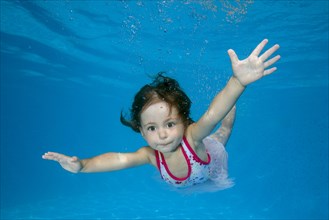 Little girl learns to swim underwater in the pool