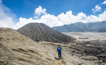 Young man on a narrow path at the crater rim of the volcano Gunung Bromo