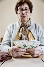 Senior citizen sits at the table and counts her money