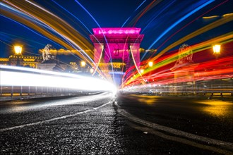 Illuminated chain bridge with traces of light at night