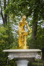 Close-up of marble water fountain with golden goddess statue