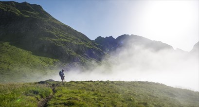 Hiker on the Schladminger Hohenweg with rising clouds of fog