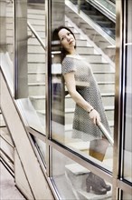 Young woman posing behind a glass wall in an underground station
