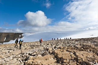 Hiking group in rocky terrain in front of Foxfonna glacier
