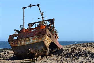 Rusty wreck of a fish trawler on the rocky shore