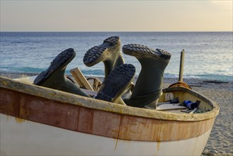 Rubber boots in a fishing boat on the beach