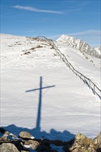 Shadow of summit cross in the snow