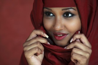 Young pretty woman with oriental look holds with hands a red scarf