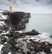 Orange lighthouse Ondverdarnes stands on a dark cliff