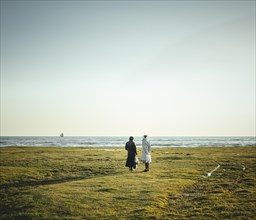 Two women standing at the coast looking at the horizon