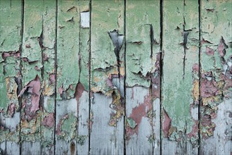 Peeling green and red paint on wooden wall