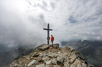 Hiker at the summit cross of Hochgolling