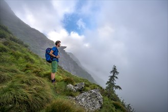 Hiker climbing the Greifenberg with wafts of mist