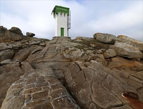 Green and white lighthouse on granite rocks