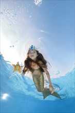 Girl in a mermaid costume poses underwater