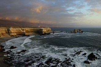 Rocky coast with arch La Portada at sunset with clouds