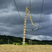Concrete electric pole broken in two by the storm in a field in the countryside