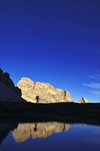 Hiker on the lake in the backlight