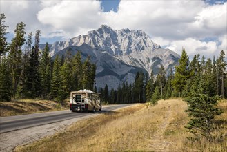 Motorhome on road in front of spectacular mountain scenery in autumn