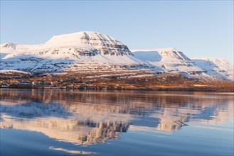Water reflection of snow-covered mountains in a fjord