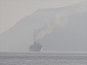 Cruise ship with smoking vent in morning mist in the Gulf of Naples at Sorrento