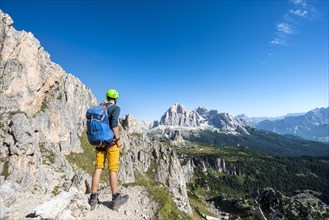 Hiker with climbing helmet on hiking trail to the Nuvolau