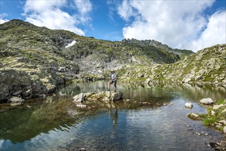 Hiker on a stone in a small lake