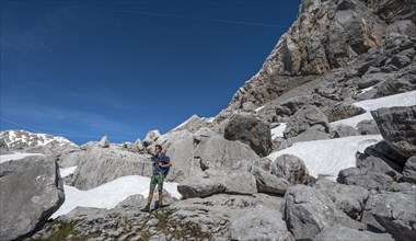 Hiker among rocks and snow remains