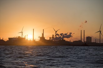 Harbour entrance with wind turbines and the Tata steelworks at sunset