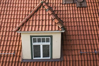 Top view of dormer window on old terracotta roof of residential apartment building