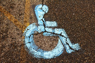 Handicapped sign on torn tar on disabled parking lot