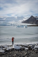 Man stands at frozen lagoon with ice floe