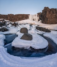 Partially frozen waterfall Oxararfoss in winter