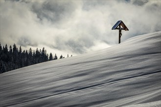Wayside cross on snowy mountain slope