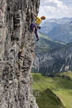 A woman climbs up a vertical rock face