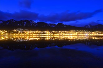 The city lights are reflected in the Beagle Channel in the blue hour