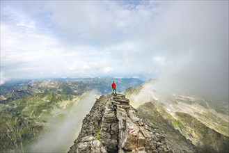 Hiker on the summit of the Hochgolling with rising fog