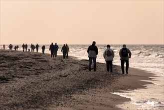People walking on the beach by evening light