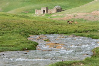 Tash Rabat with horses on meadow and mountain river