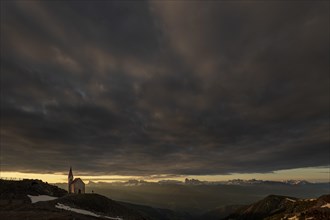 Latzfonser cross chapel at sunrise with dramatic clouds and South Tyrolean mountains
