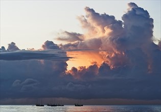 Fishing boats at sunrise in front of dramatic clouds