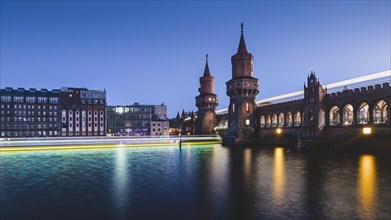 Berlin Oberbaum Bridge with traces of light from ship and train in the evening