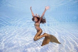 Girl in a mermaid costume poses underwater in a pool