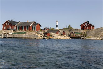 Red wooden houses with lighthouse on the rocky coast
