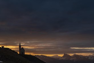 Latzfonser cross chapel at sunrise with dramatic clouds and South Tyrolean mountains