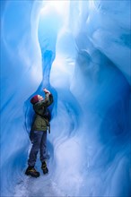 Woman photographing in a ice cave in Fox Glacier